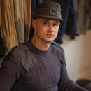Man wearing a genuine Finnish army M65 field cap in gray wool with double-button neck flap, vintage military style.