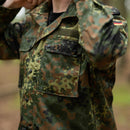 Close-up of Leo Kohler tactical military shirt in flecktarn camouflage with pockets and German flag patch on sleeve