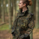 Man wearing TACGEAR German Flecktarn tactical smock jacket with YKK zipper standing in forest background