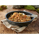Dehydrated vegetarian wild mushroom meal in black bowl with spoon on rustic cloth and wooden surface outdoors