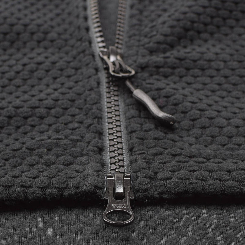 Close-up of black textured fleece fabric with sturdy metal zipper on military style thermal jacket