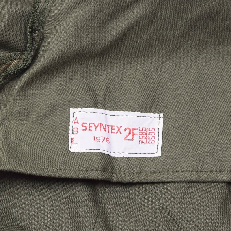 Close-up of genuine Belgian military jacket label sewn inside an olive green vintage BDU hooded parka.