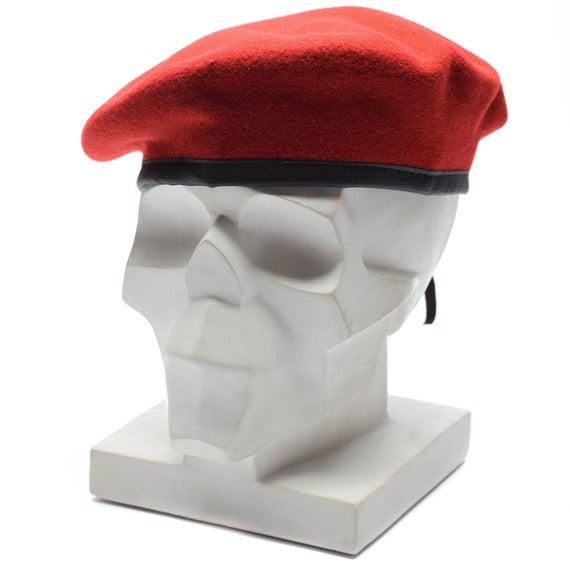 Oryginalny beret z czerwonej wełny armii niemieckiej, prezentowany na białym, nowoczesnym modelu głowy z rzeźbą z czarną lamówką.
