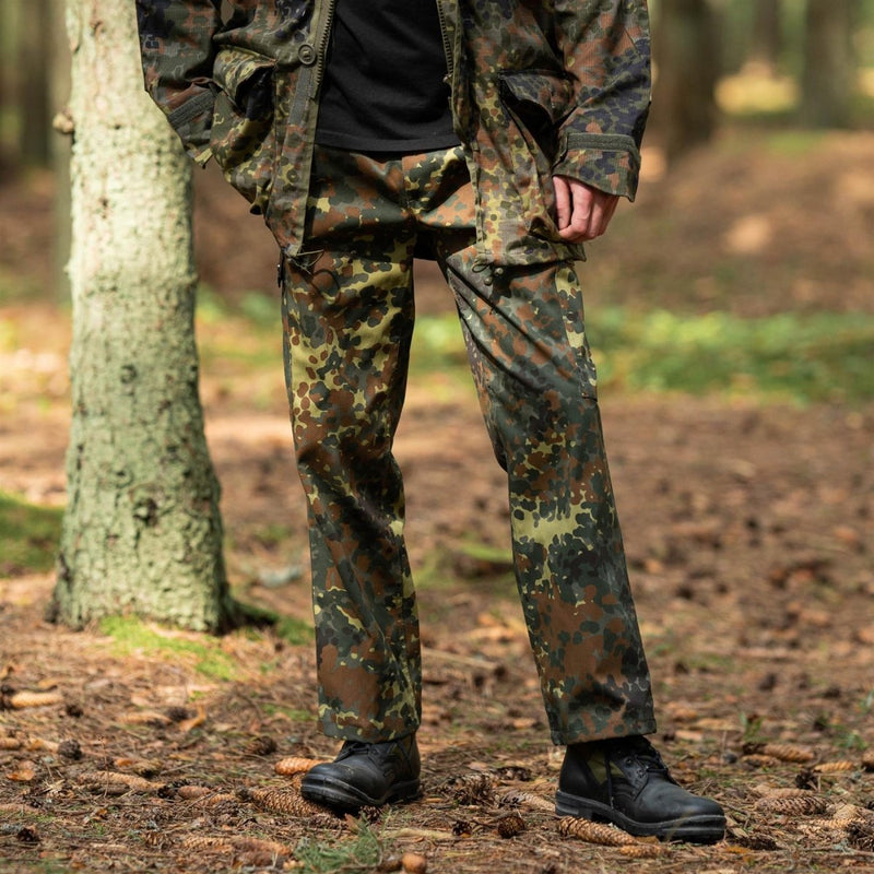 Man wearing German flecktarn camo military style field cargo pants standing in a forest setting