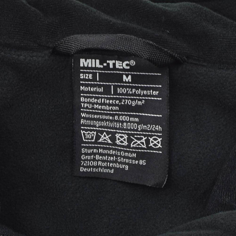 Close-up of MIL-TEC fleece jacket label showing size medium, 100% polyester bonded fleece with TPU membrane and care instructions.