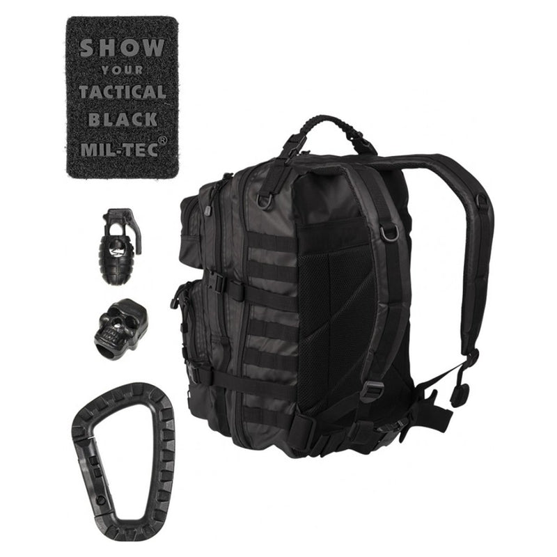 Black MIL-TEC U.S. Assault tactical backpack with patches, grenade, skull accessory, and carabiner for hiking and camping.