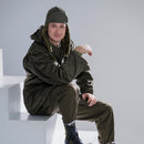 Man wearing an original Austrian army M65 olive drab combat jacket and matching military pants sitting on white steps