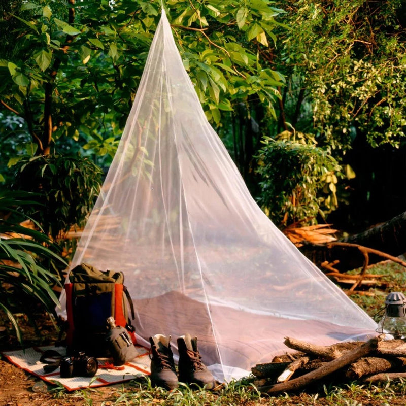Mosquito net set up outdoors with camping gear on a grassy area.